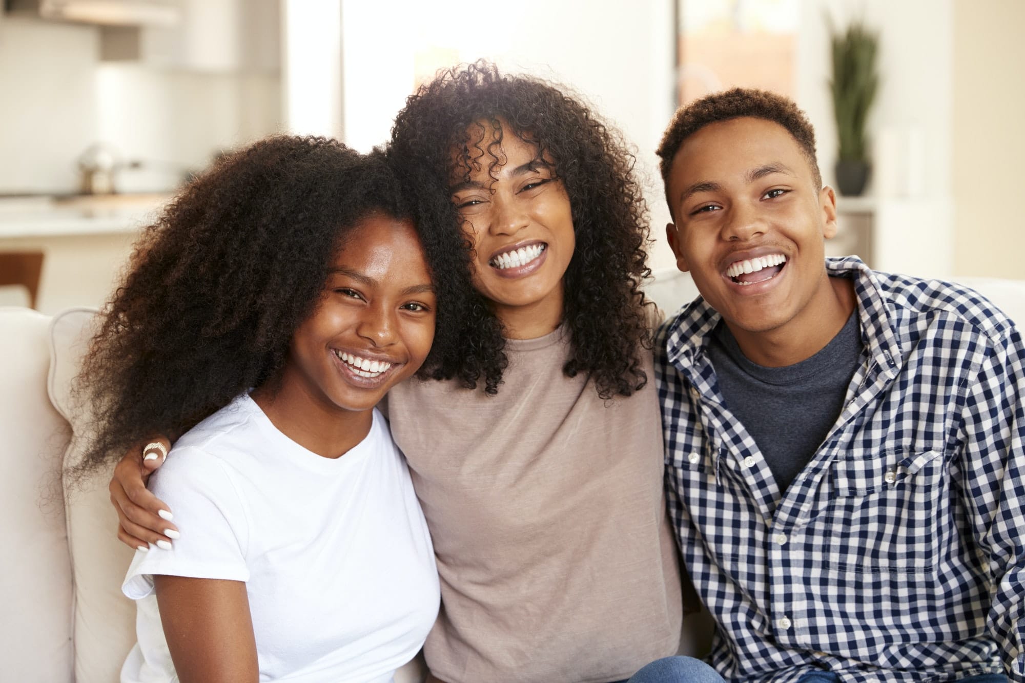Black teen and young adult brother and sisters smiling to camera, close up