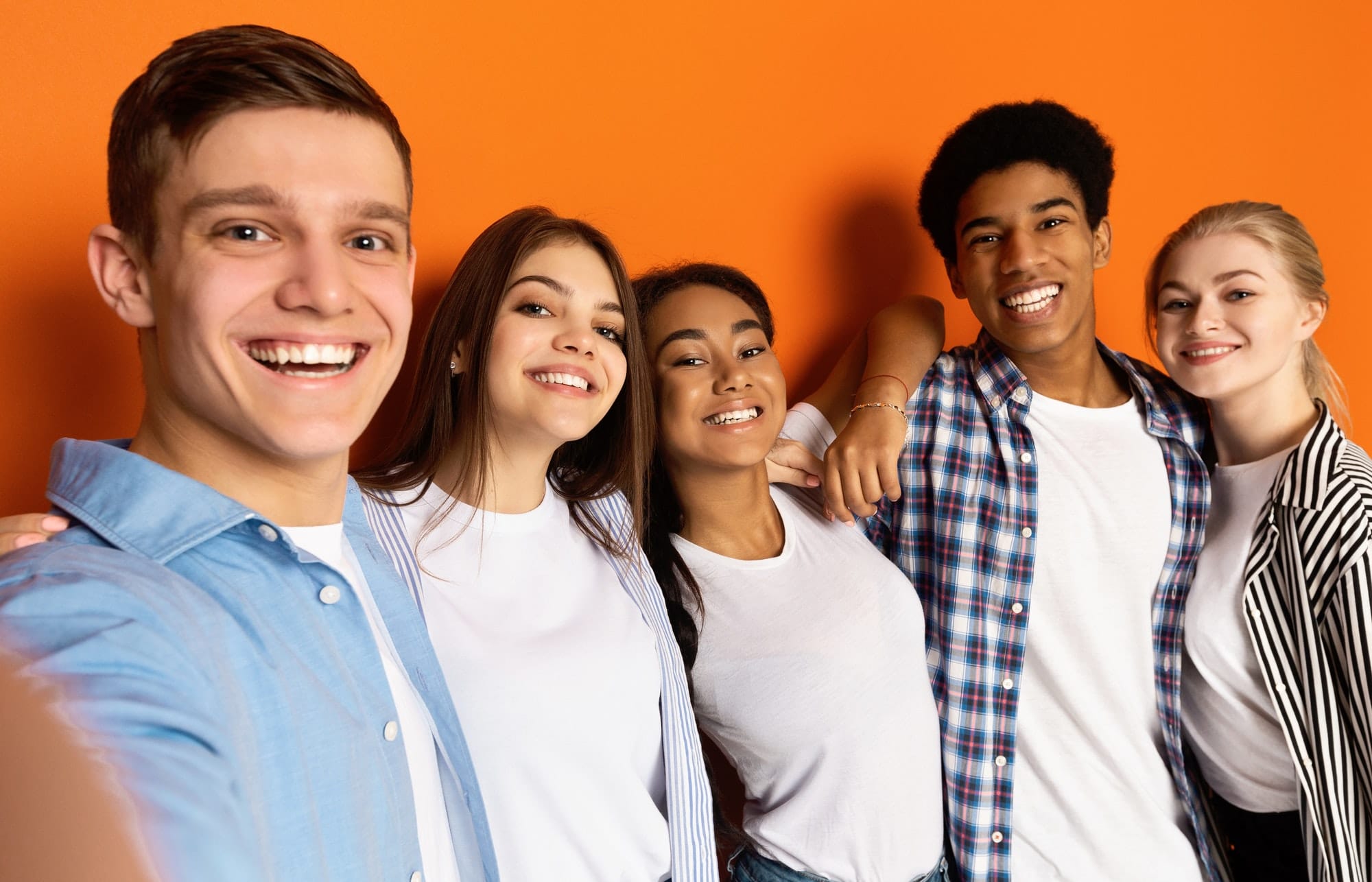 Teen friends making selfie and having fun, orange background